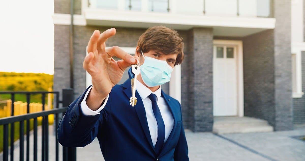 Male in medical mask holding house key